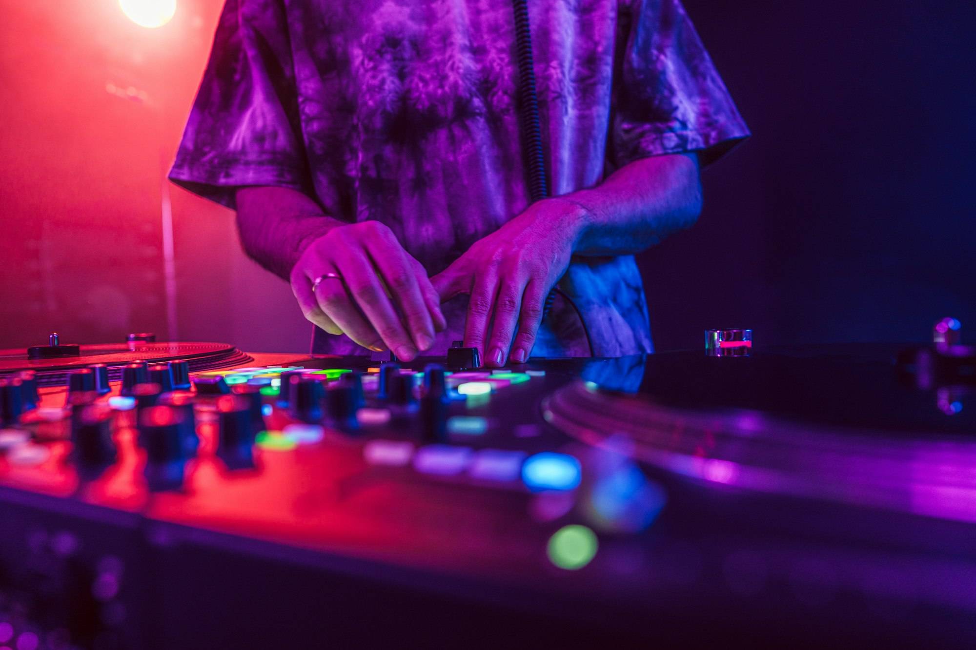 Close up of DJ hands on dj console mixer during concert in the club