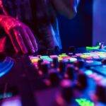 Close up of DJ hands on dj console mixer during concert in the club